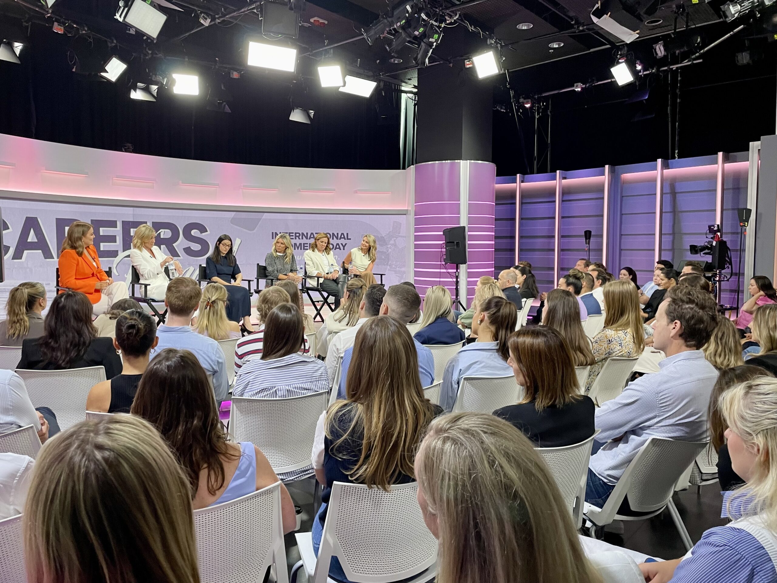 International Women's Day event showing panel on stage with Nine employees watching